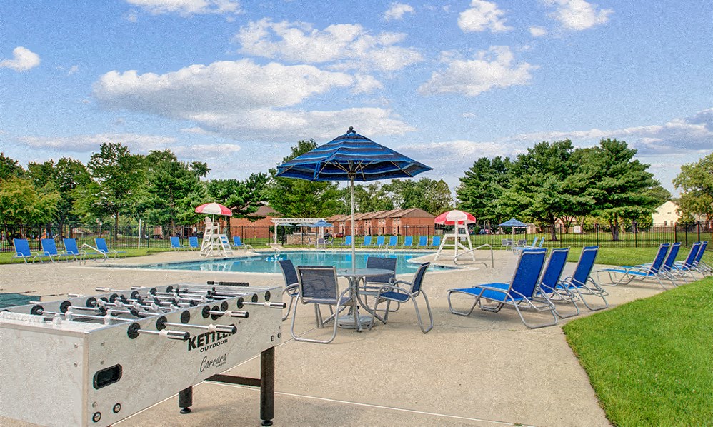an outdoor pool with chairs and umbrellas and a shuffleboard