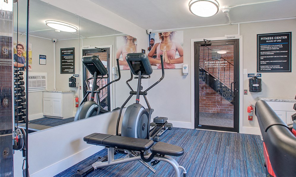 a gym with cardio equipment and a poster of women on the wall