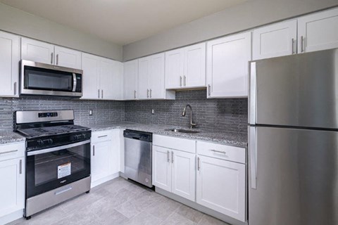 a kitchen with white cabinets and stainless steel appliances