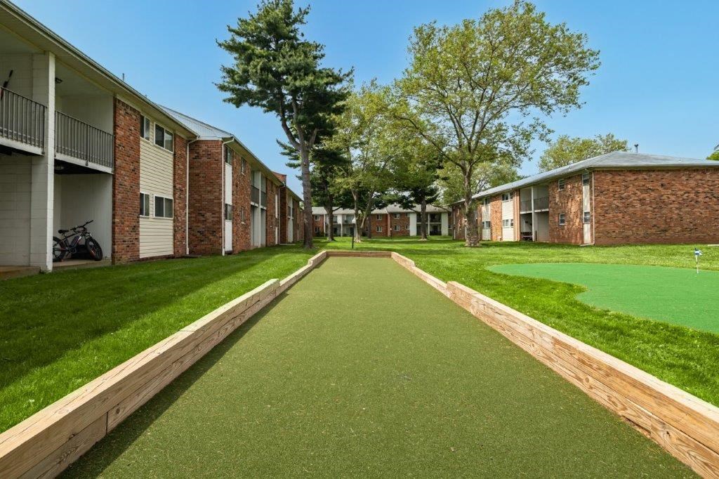 a walkway between two apartment buildings with grass and trees