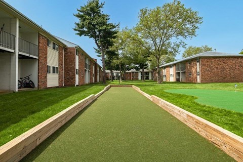a walkway between two apartment buildings with grass and trees