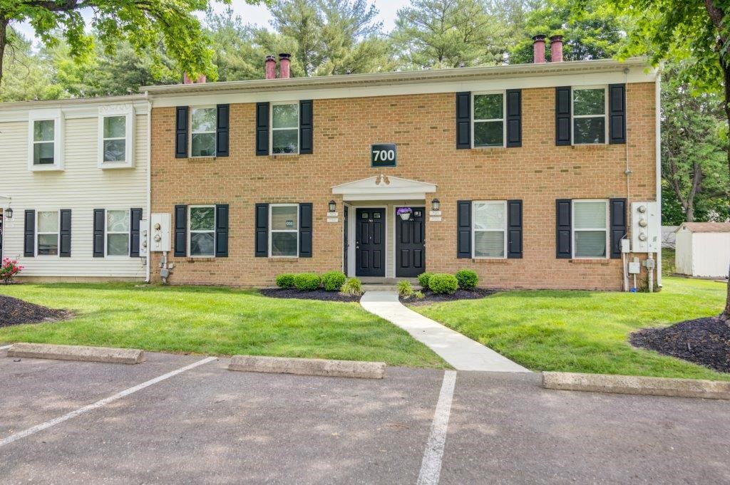 the front of a brick house with a sidewalk and grass