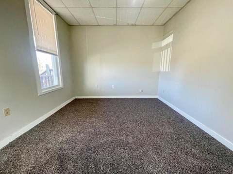 A room with a carpeted floor and a window.