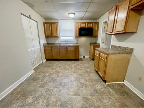A kitchen with wooden cabinets and a microwave.