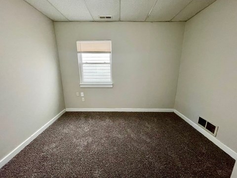 A room with a window and carpeted floor.