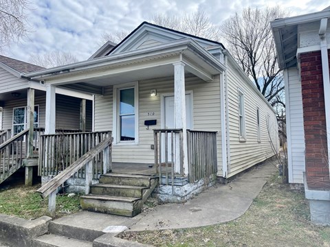 A small house with a porch and a mailbox on the front door.