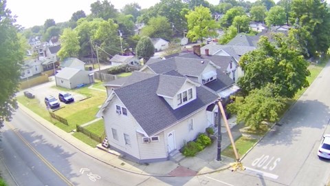 A house with a grey roof is surrounded by green trees.