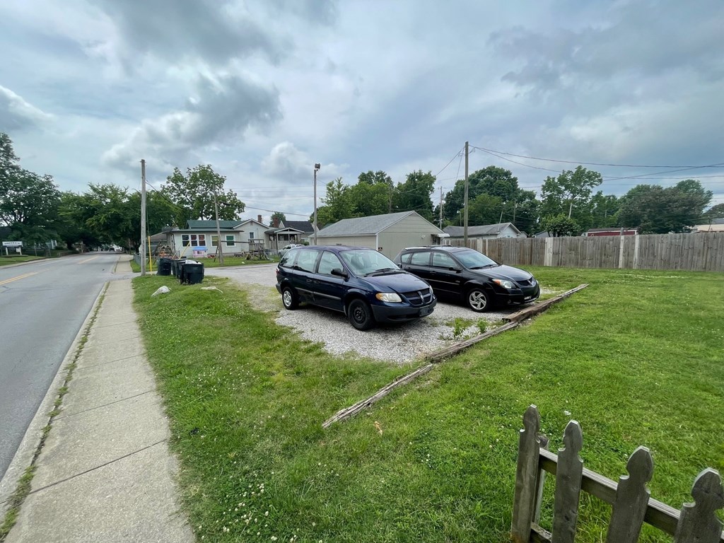 Two cars parked on a grassy area next to a sidewalk.