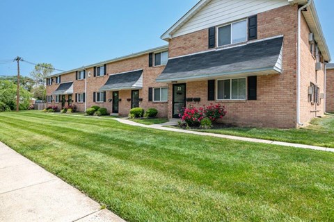 a brick house with a lawn and a sidewalk