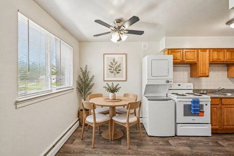 A kitchen with a table and chairs in front of a window.