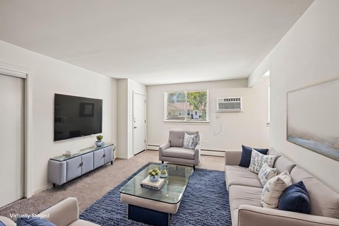 A living room with a glass coffee table and a television on the wall.