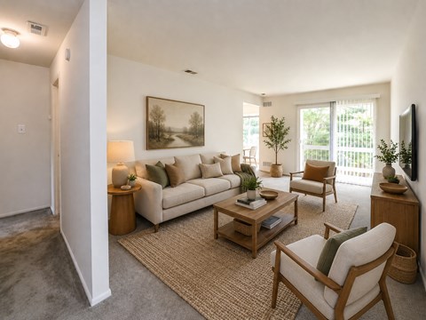 A living room with a couch, chair, and a painting on the wall.