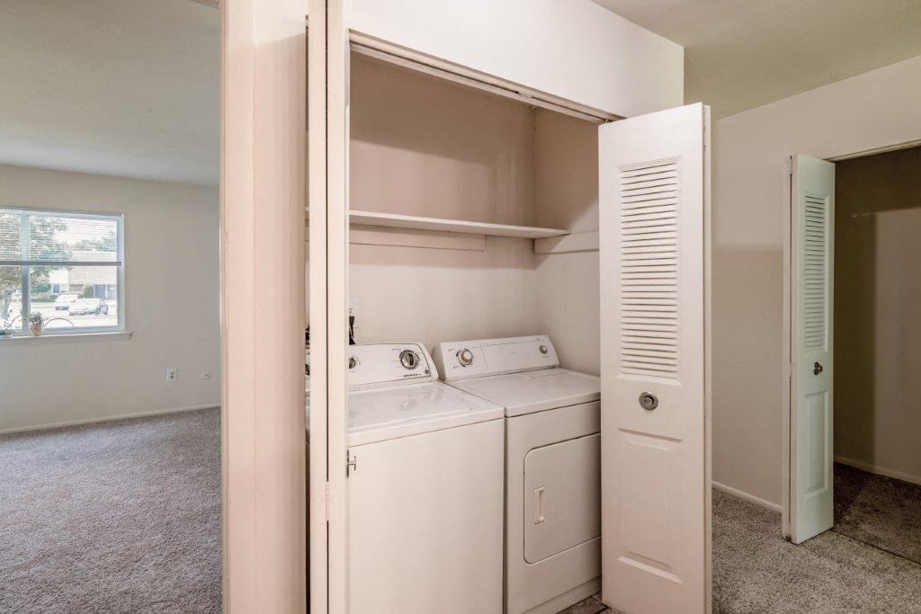 an empty laundry room with white appliances and a closet