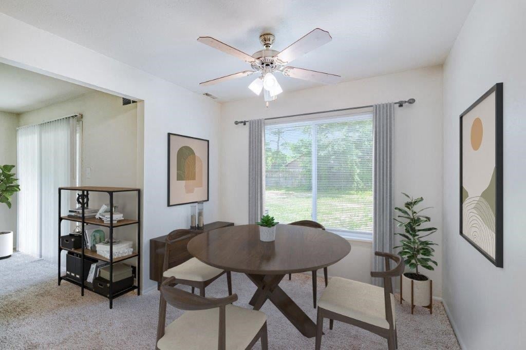 a dining room with a large window and a ceiling fan