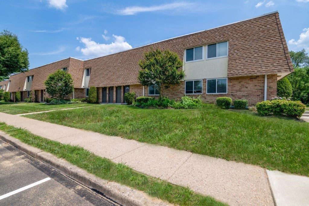 the front of a brick house with a sidewalk and grass