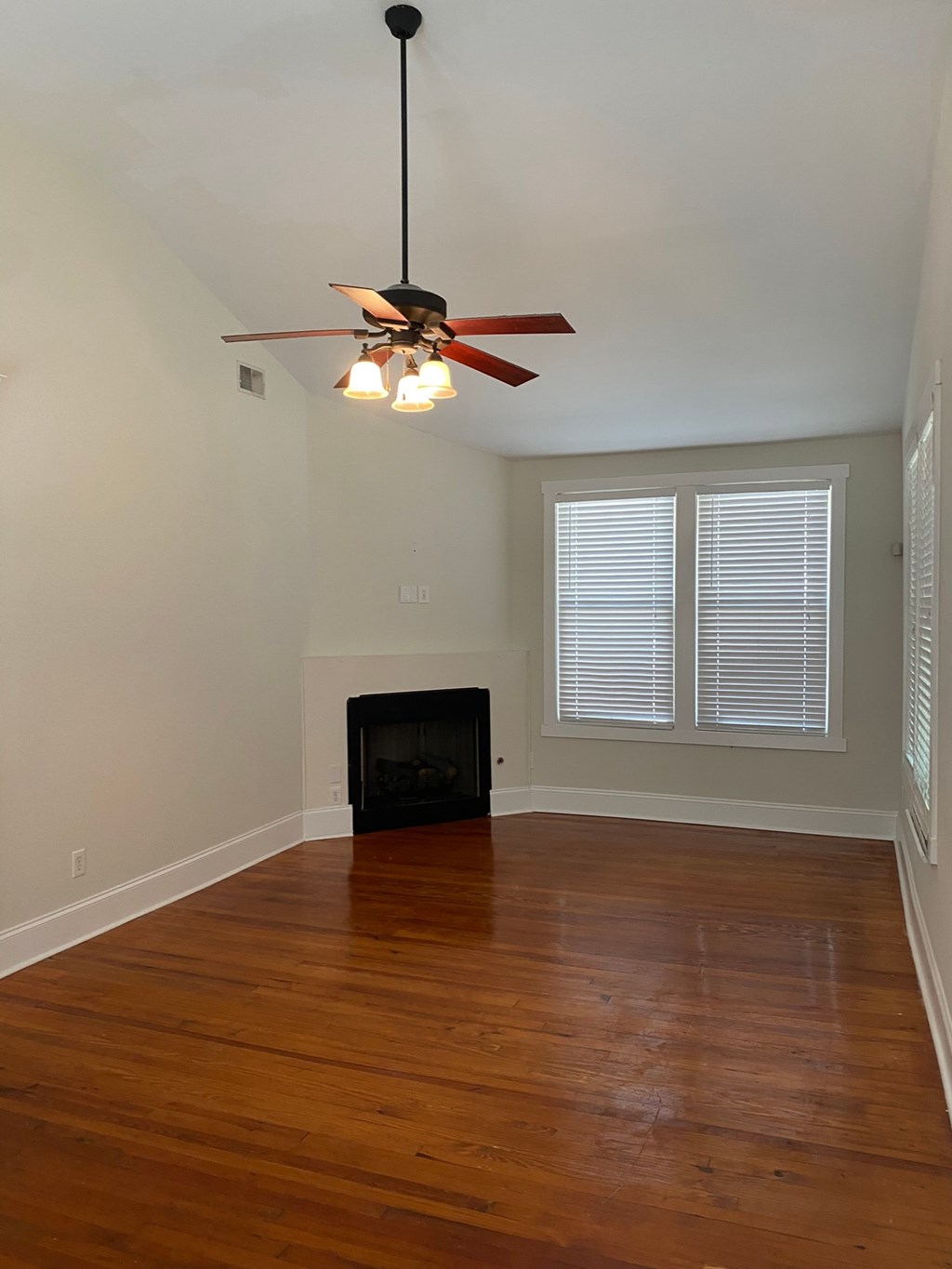 A room with a ceiling fan and wooden floors.