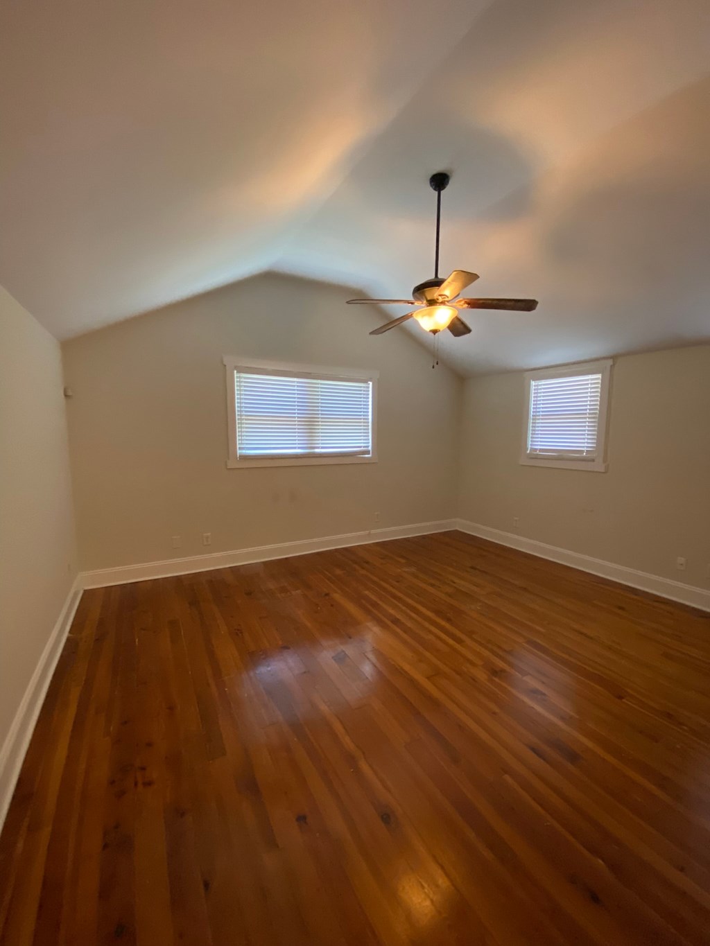 A room with a ceiling fan and wooden flooring.