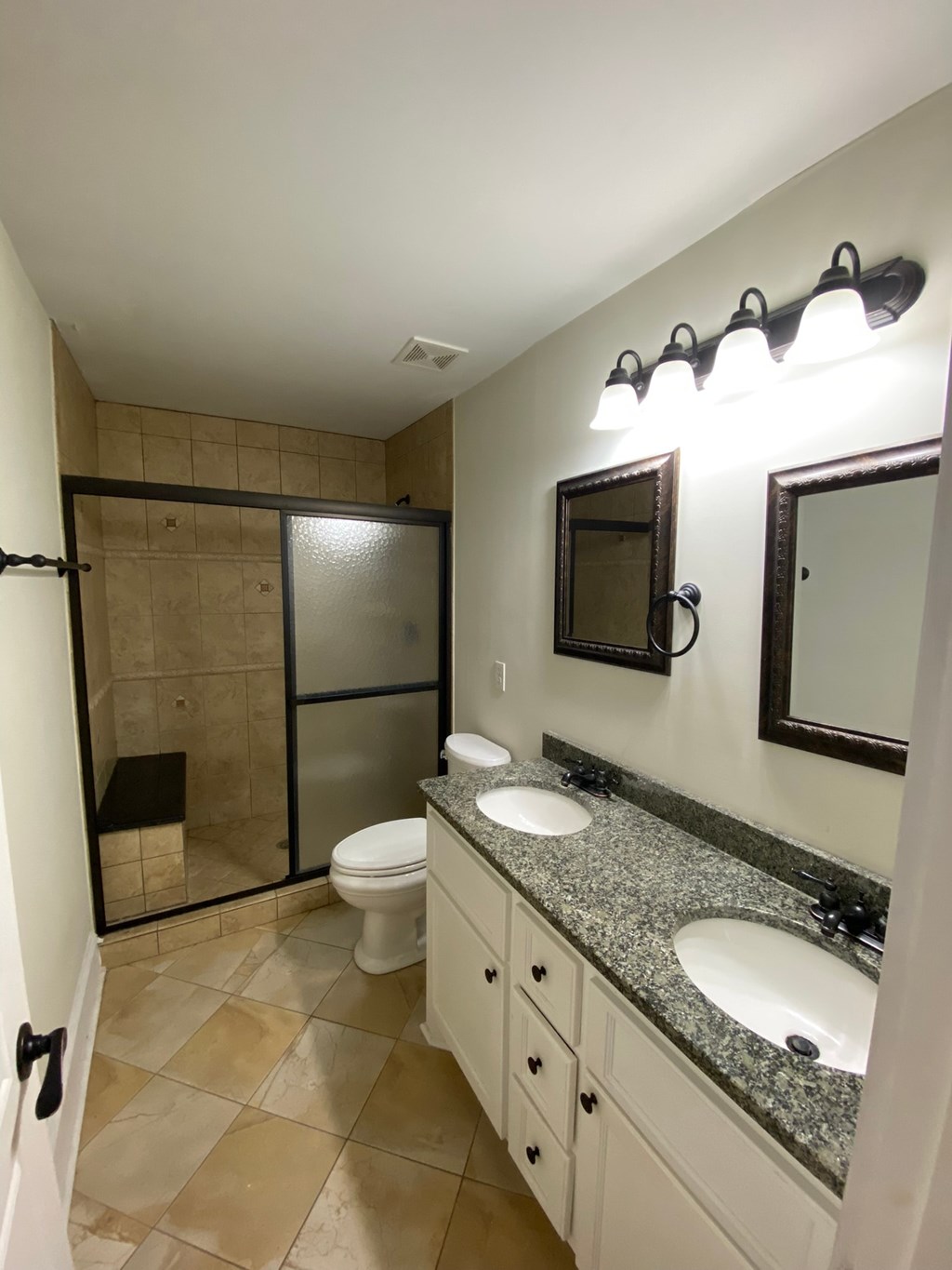 A bathroom with a toilet, sink, and mirror.
