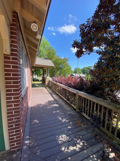 A wooden deck with a railing and a brick building.