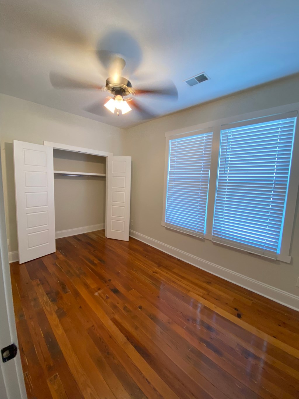 A room with a ceiling fan and wooden floors.