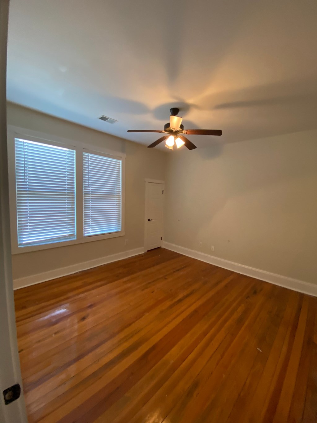 A room with a ceiling fan and wooden flooring.