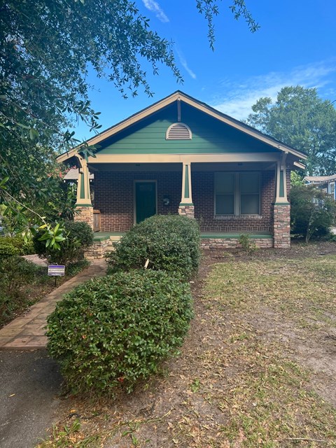 a small brick house with a green roof and a sidewalk