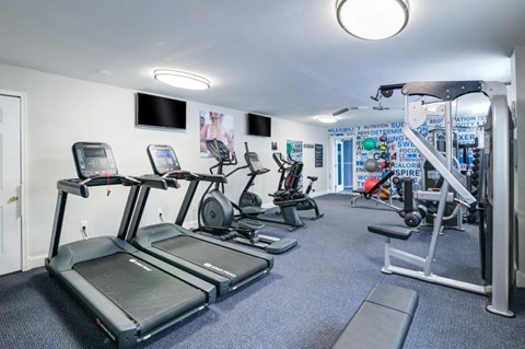 a gym with cardio equipment and a tv in a building