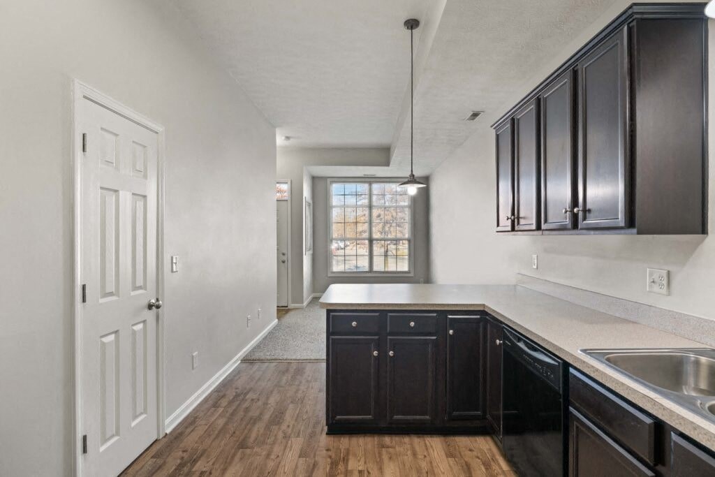 an empty kitchen with black cabinets and a door to a hallway