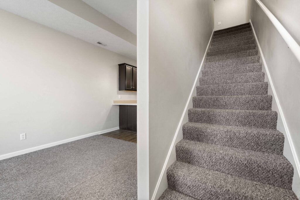 a carpeted staircase in a home with white walls and gray carpet floors