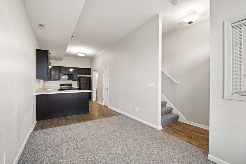 a renovated living room and kitchen with white walls and wood floors