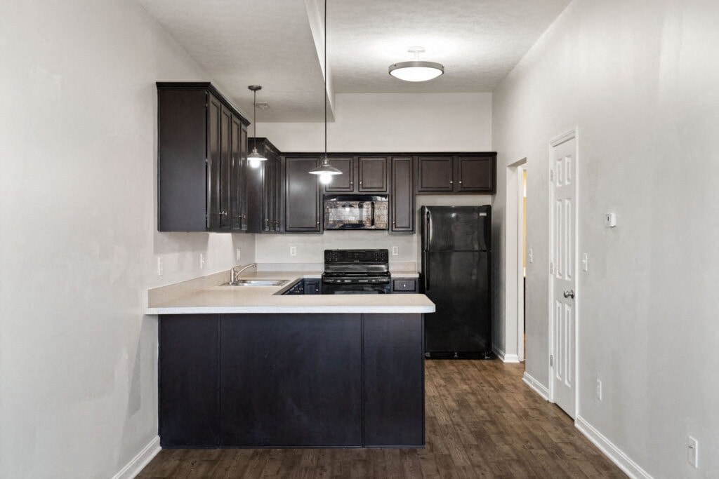 an empty kitchen with black appliances and dark cabinets