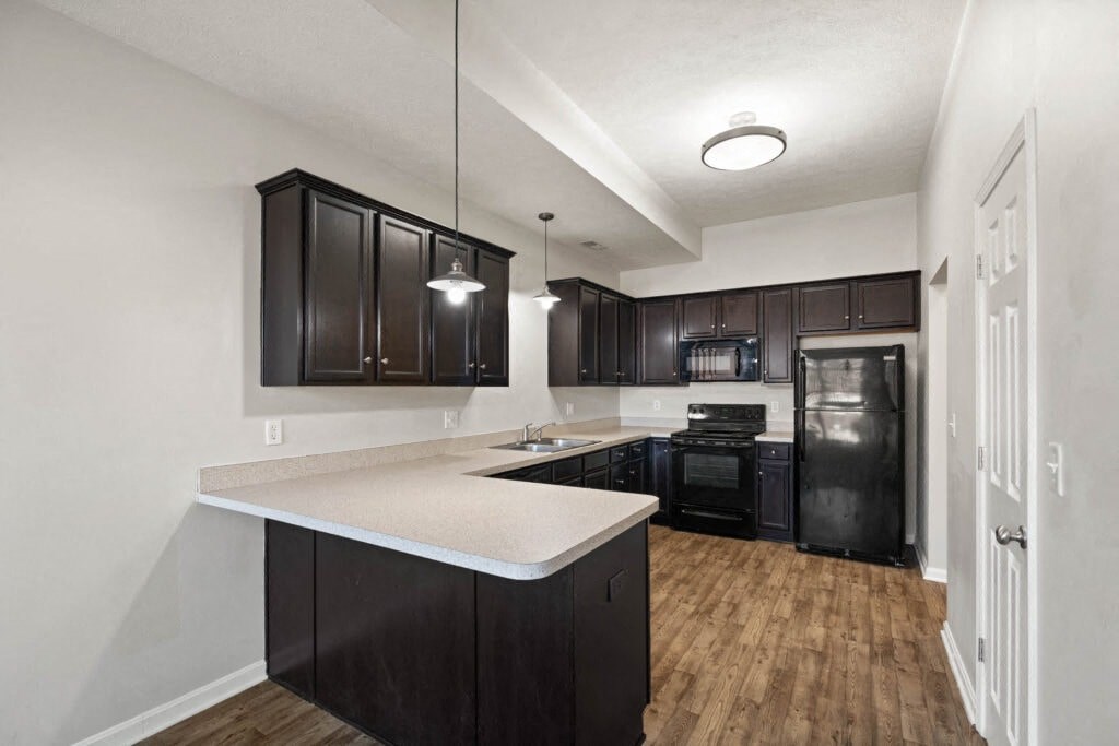 an empty kitchen with black cabinets and a white counter top
