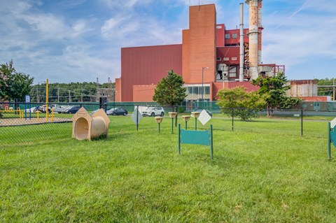 a park with agility equipment and a factory in the background