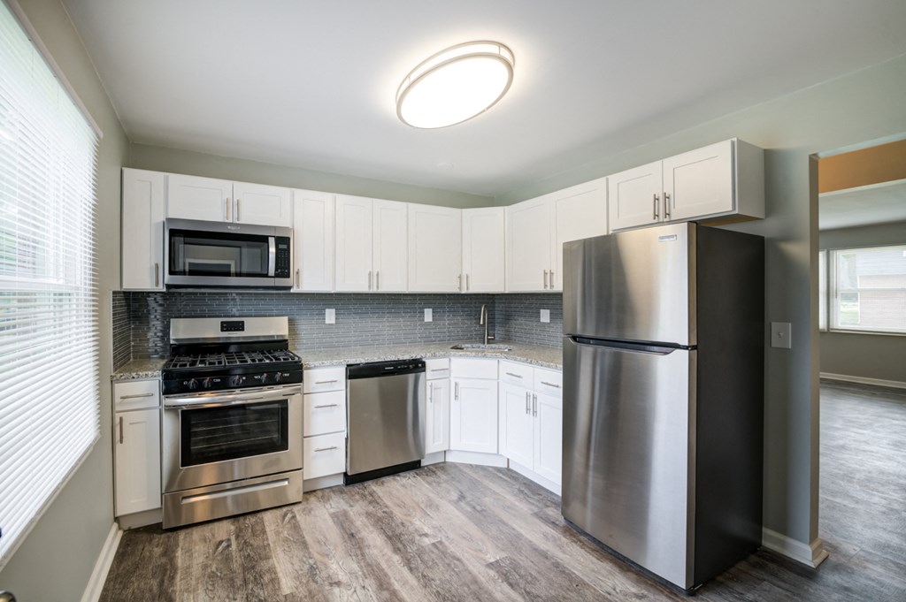 an empty kitchen with stainless steel appliances and white cabinets