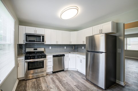 an empty kitchen with stainless steel appliances and white cabinets