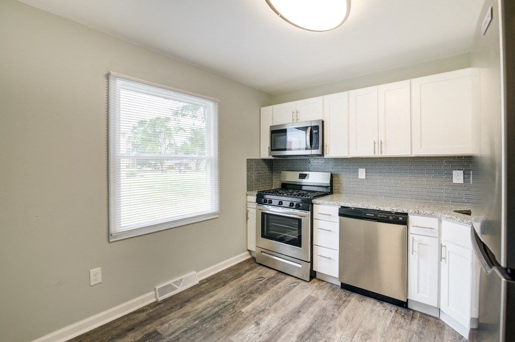 a kitchen with white cabinets and stainless steel appliances and a window