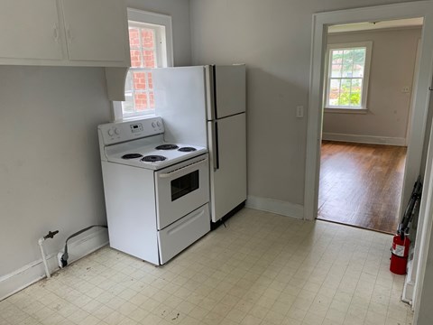 A white kitchen with a stove and refrigerator.