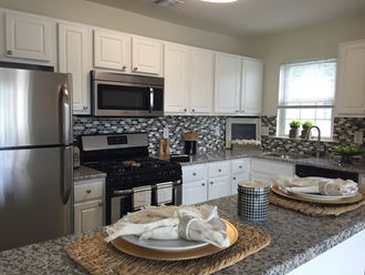a kitchen with white cabinets and granite counter tops and stainless steel appliances