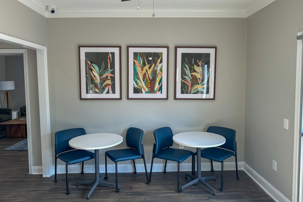 A room with a table and chairs and two pictures on the wall.