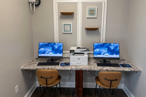 A workspace with two computers, a printer, and two chairs.