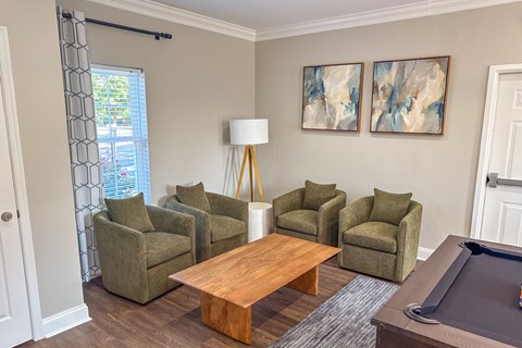 A living room with a pool table and a few chairs.