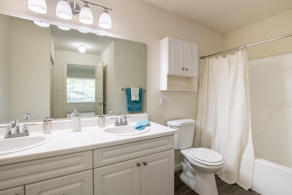 Bathroom with white vanity, large mirror, and tub/shower