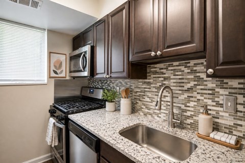 A kitchen with brown cabinets and a stainless steel sink.