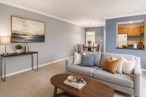 A living room with a grey couch, a wooden table, and a painting on the wall.