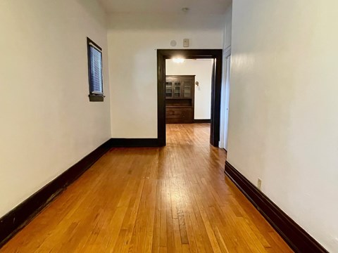 A hallway with wooden floors and white walls.