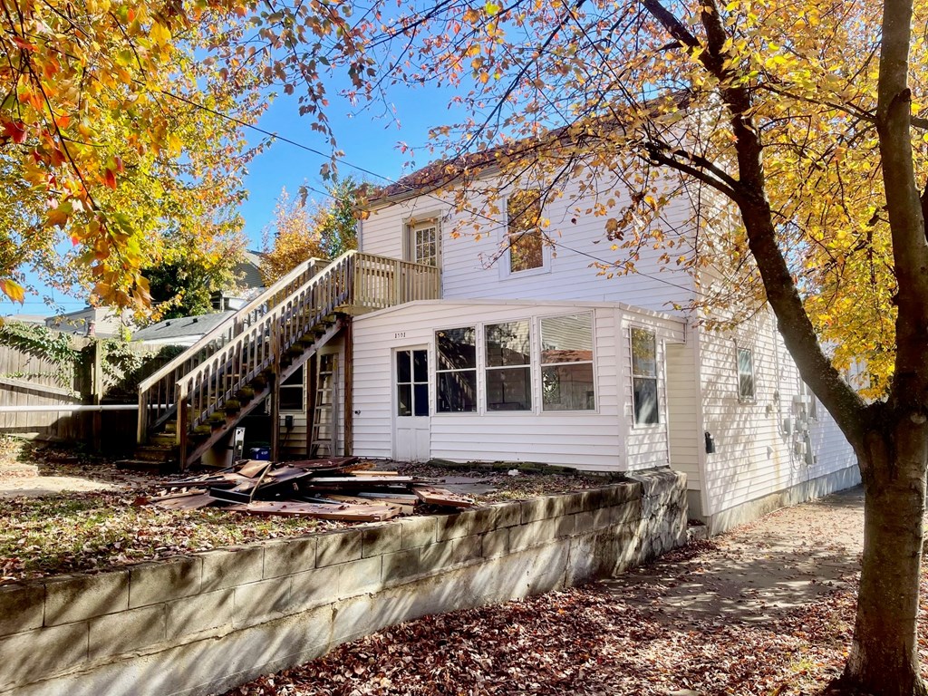 A house with a white exterior and a stone wall in front.