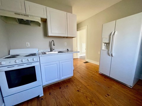 A kitchen with a white stove and refrigerator.