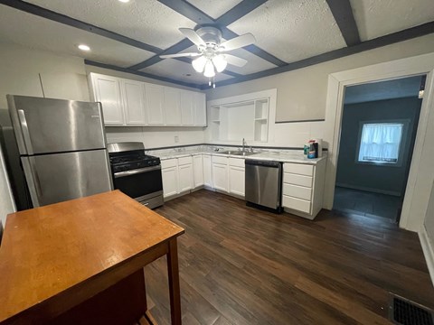 A kitchen with a wooden table and a refrigerator.