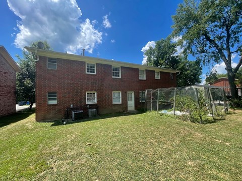 A red brick house with a white roof and a green lawn in front.