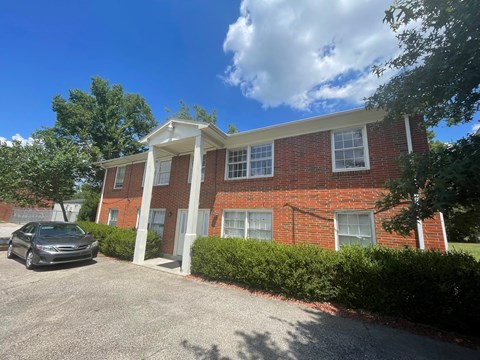 A brick house with a car parked in front.